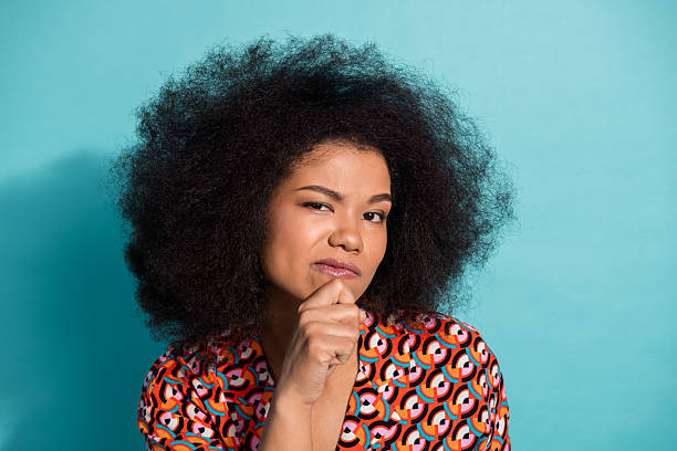 istock Young female model with curly afro hairstyle thoughtful expression wearing colorful geometric shirt against blue background for fashion lifestyle advertising 2242323621
