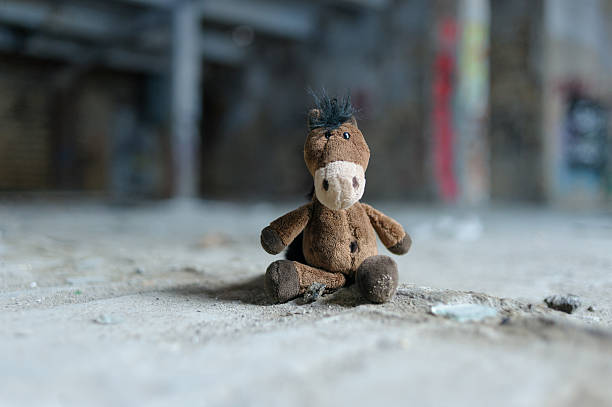 Close-up of a soft brown plush horse toy sitting against a beautiful blurred background, creating a warm and gentle composition.