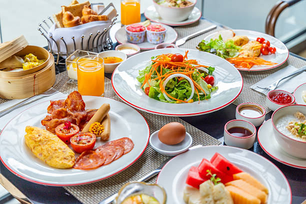istock Varied breakfast spread on table with omelet, bacon, salad, fruit, dim 2242328356