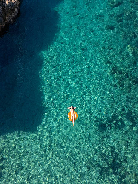 istock Woman Relaxing on Inflatable Ring in Clear Water 2242329413