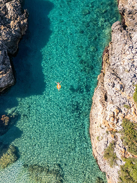 istock Woman Floating on Clear Water Between Rocks 2242329531