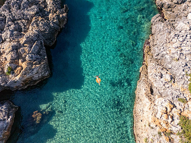 istock Woman Floating on Clear Water Between Rocks 2242329735