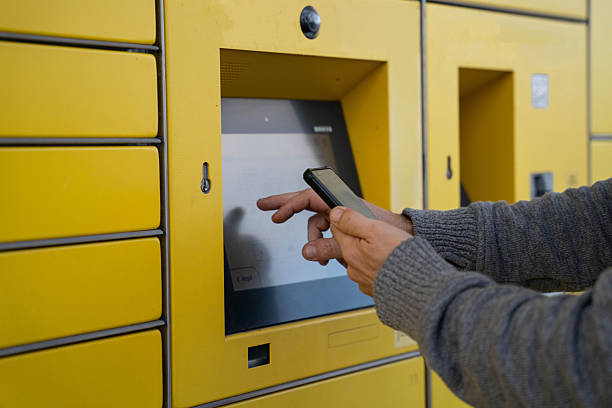 istock Person using smartphone and touchscreen terminal on yellow parcel locker for online delivery pickup 2242329885