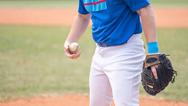 istock Young Caucasian Baseball Pitcher Holding Ball and Glove on Mound 2242331554