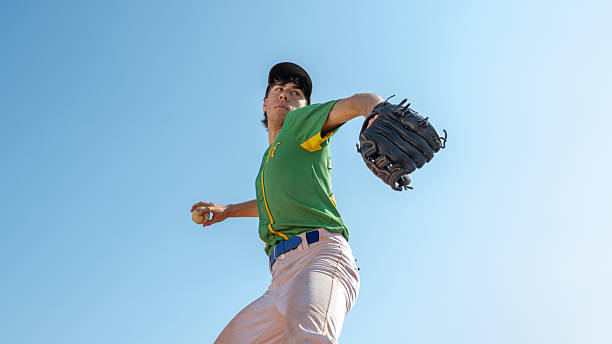 istock Caucasian Male Pitcher Energetically Throwing Baseball on Field During Sunny Day Game 2242331568