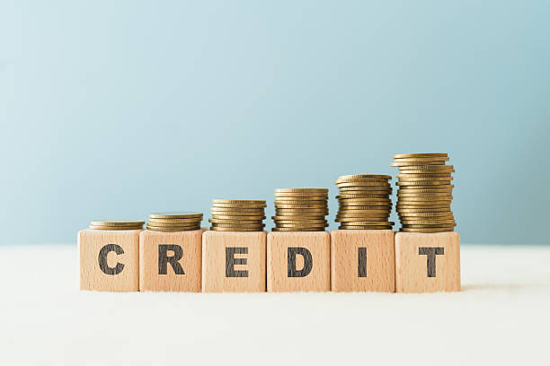 istock CREDIT text on wooden cube blocks with stack of coins above, blue background, copy space 2242332987