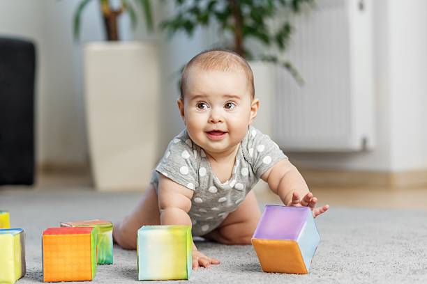 istock Smiling baby playing with colorful soft blocks on floor. Developmental Milestones 2242336694