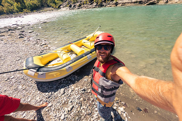 istock Man Taking Selfie Near Raft on Rocky Riverbank 2242336784