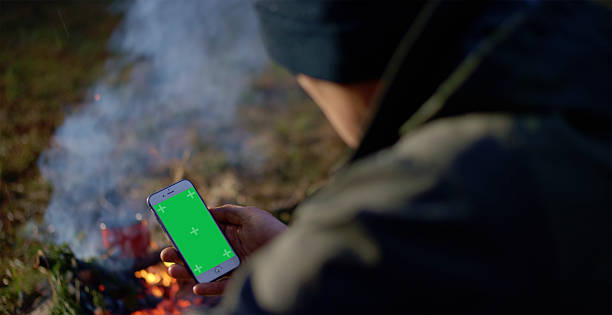 istock Caucasian Male Using Smartphone with Green Screen by Campfire in Forest 2242337241