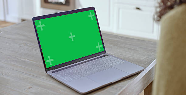 Close up shot of a female working from home using a laptop with a green screen display featuring a modern home office setting. The scene highlights a casual and focused work environment, emphasizing remote work dynamics and digital connectivity.