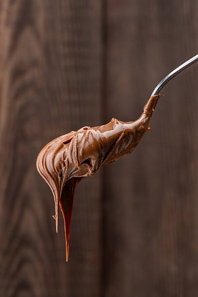 istock Cream chocolate in a spoon on a wooden background 2242338080