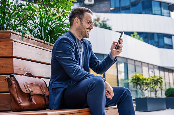 istock Smiling businessman checking phone outside corporate office 2242339849