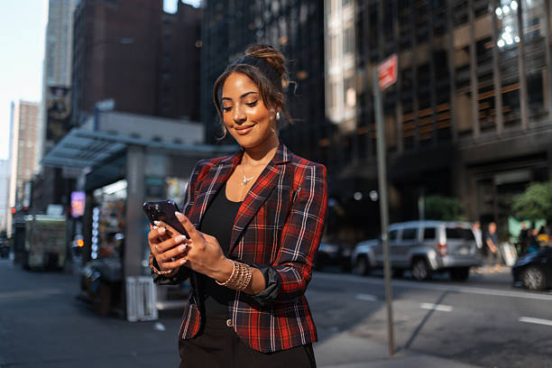 istock Woman smiling using smartphone on city street 2242340536