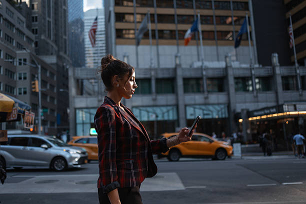istock Woman checking smartphone while walking in new york city 2242340541