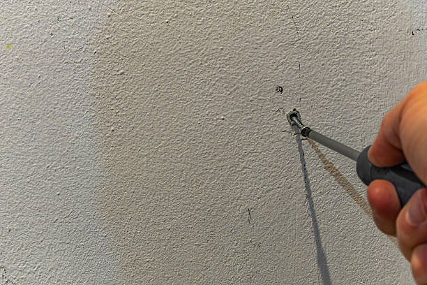 istock Male hand using a screwdriver to fasten a screw into a wall anchor. 2242342637