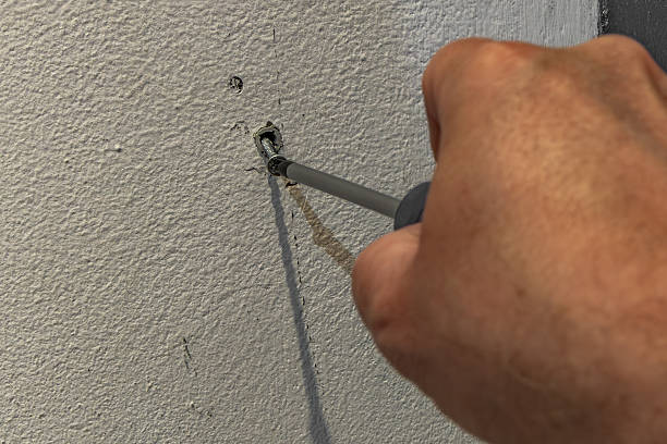 istock Male hand using a screwdriver to fasten a screw into a wall anchor. 2242342639