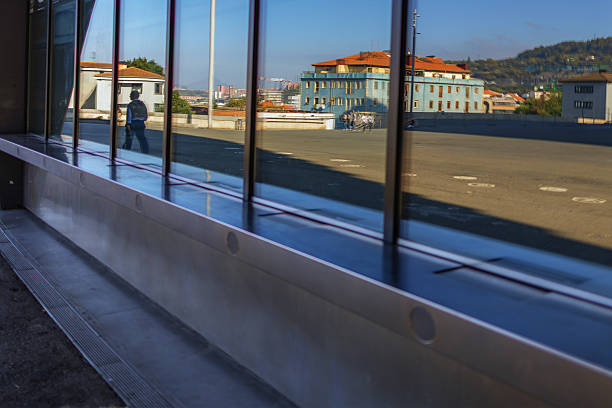 A man walks past a building window and is reflected