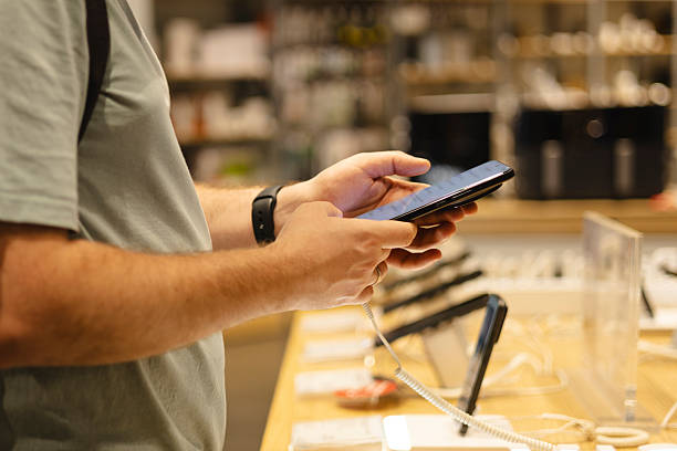 istock Closeup of man testing smartphone at electronics store showcase. 2242347751