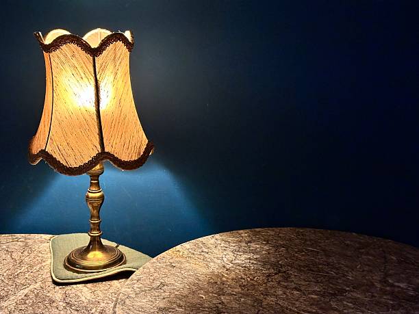 istock Vintage table lamp glowing warmly on a marble surface against a dark blue wal 2242351277