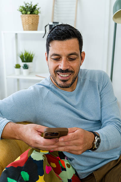 istock Mid adult man smiling while using smartphone indoors 2242354176