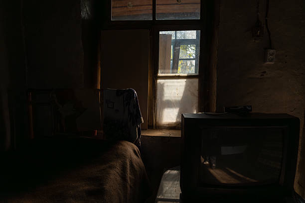 istock Low-lit abandoned room with vintage television and window light 2242354227