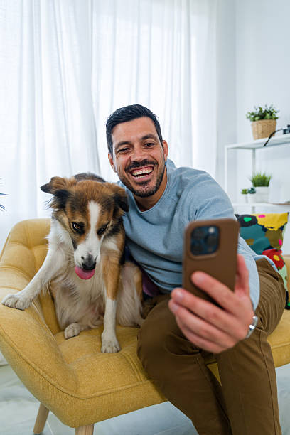 istock Happy man taking selfie with dog on sofa 2242354777