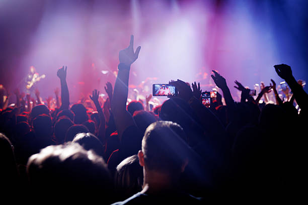 istock Fans raise hands at rock concert with stage lights 2242354859
