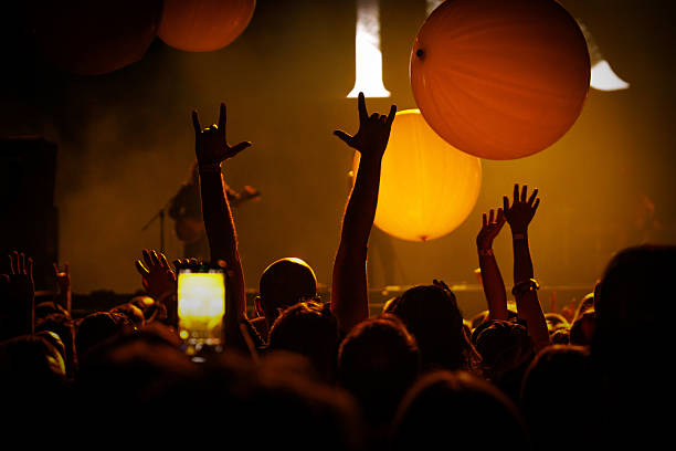 Silhouetted hand reaching up at a live music event, illuminated by dramatic stage lighting. Symbolizes unity, excitement, and immersive concert atmosphere.