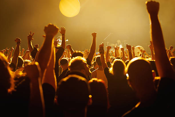 istock Excited concert crowd raising hands under bright stage lights 2242354877