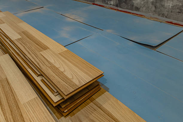 istock Wood laminate flooring installation on blue underlay during home renovation process 2242355235