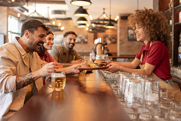 istock Happy Customers Enjoying Burgers and Beer Served by Smiling Bartender 2242355903