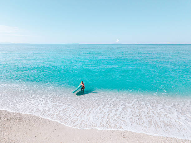 istock Woman Standing in Shallow Ocean Water with Paddleboard 2242356698