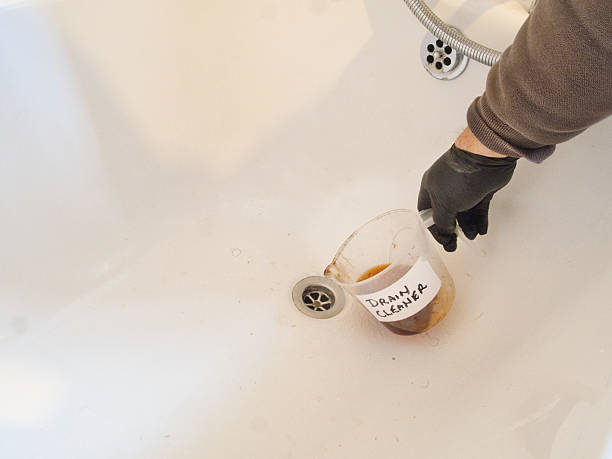 istock Pouring orange chemical cleaner into a bath drain pipe 2242359490
