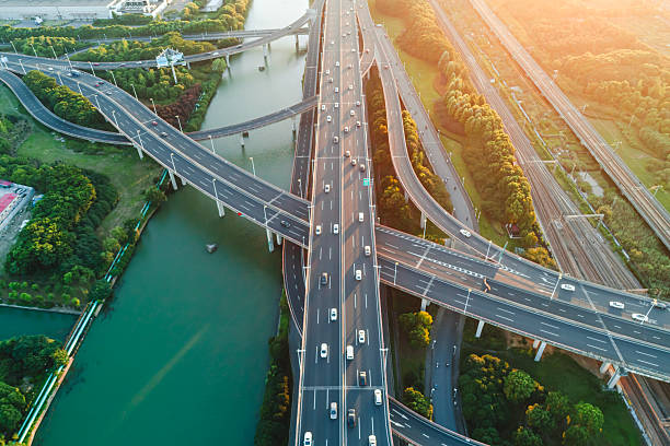 istock Aerial view of multiple highways intersect above a calm river, surrounded by vibrant greenery. 2242360080