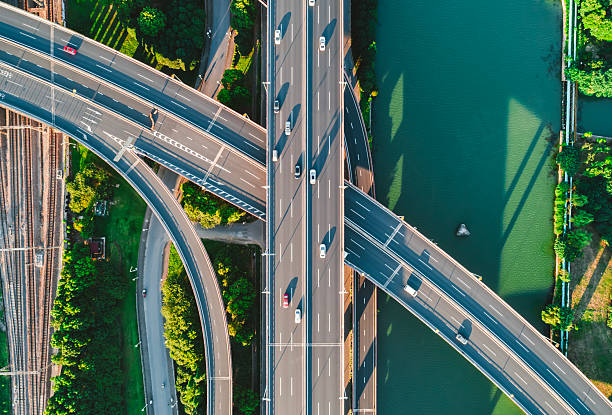 istock Aerial view of multiple highways intersect above a calm river, surrounded by vibrant greenery. 2242360301