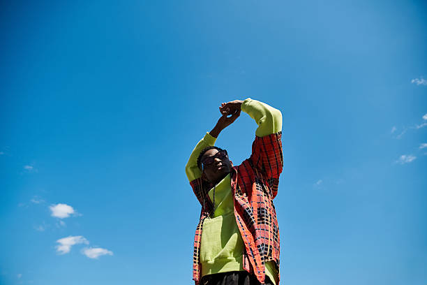 istock Young handsome man stretching under a bright blue sky in stylish attire 2242367136