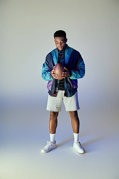 istock Stylish young man holding a football in a modern studio setting 2242367184