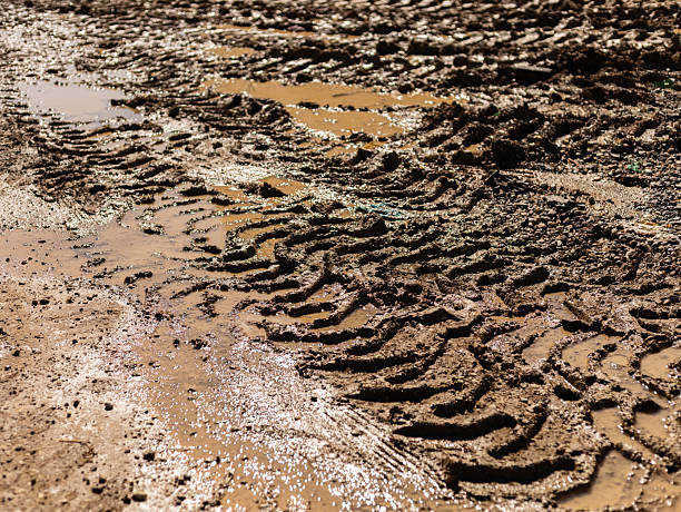 istock Tire tracks create intricate patterns in wet mud at a rural construction site. Puddles form in the low areas, reflecting the sky. The scene highlights the effects of rain on the terrain 2242367997