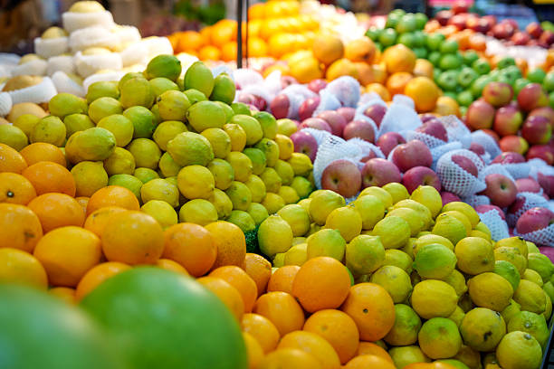 A colorful display of assorted citrus fruits including oranges, lemons, and limes arranged in piles at a fruit market. The vibrant mix of colors and textures represents freshness, healthy eating, and the abundance of seasonal produce.