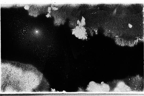 Abstract black and white photograph showing a rough, weathered surface with visible film grain and texture.