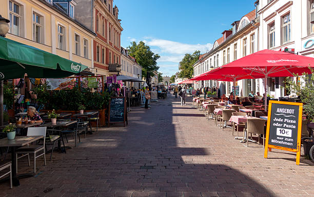 Germany, Potsdam, Downtown, September 11, 2025 - Restaurants and people in Potsdam's pedestrian zone, with parasol, table and chairs