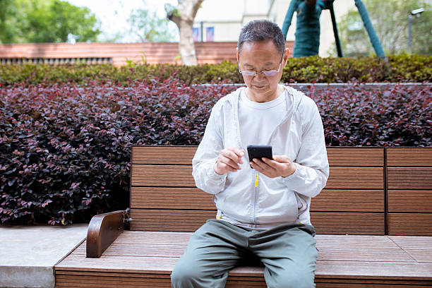 istock An elderly Asian man browsing the internet using his mobile phone outdoors 2242380519
