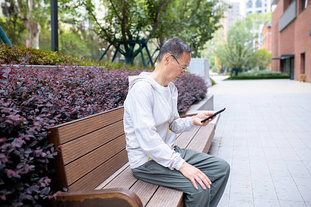 istock An elderly Asian man browsing the internet using his mobile phone outdoors 2242380524