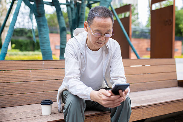 istock An elderly Asian man browsing the internet using his mobile phone outdoors 2242381271