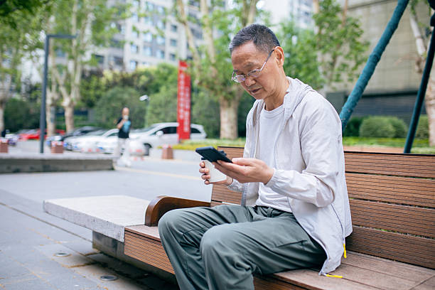 istock An elderly Asian man browsing the internet using his mobile phone outdoors 2242381287