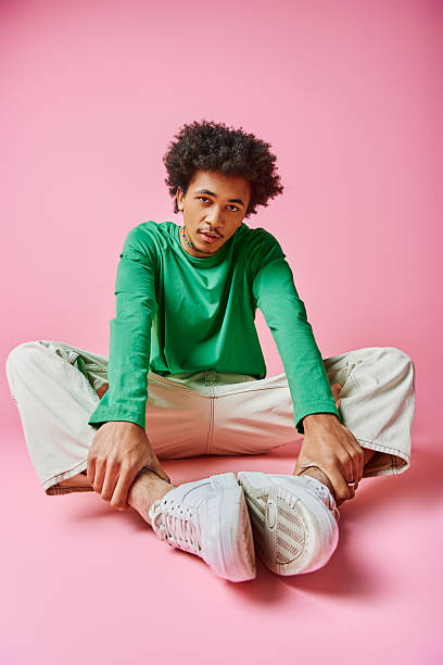istock Stylish young man poses expressively against a vibrant pink background creating a bold statement 2242381319
