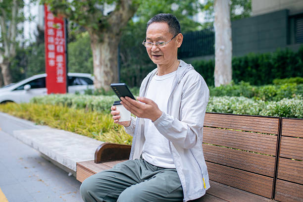 istock An elderly Asian man browsing the internet using his mobile phone outdoors 2242381328