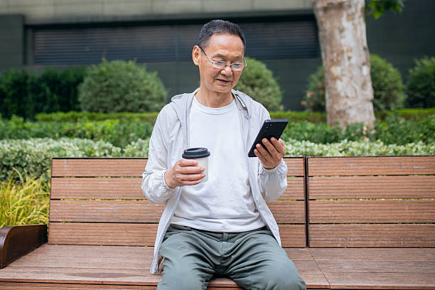 istock An elderly Asian man browsing the internet using his mobile phone outdoors 2242381341