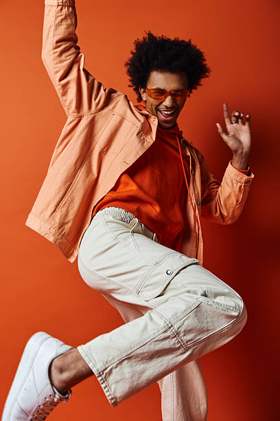 istock Stylish young man joyfully expressing emotions against a vibrant orange backdrop 2242381468