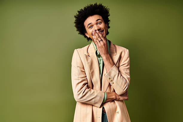 istock Charming young man expresses joy with a playful smile against a soft green backdrop 2242387420